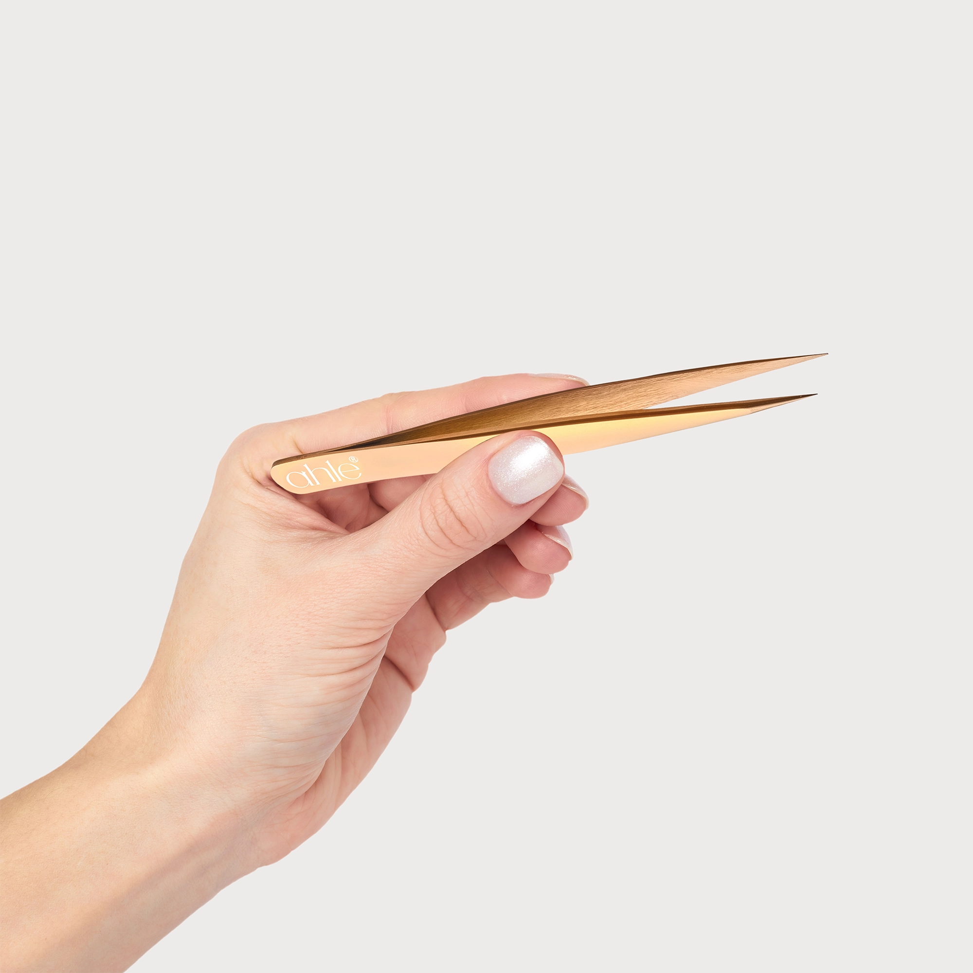 Hand demonstrating precise grip and control of rose gold tweezer set